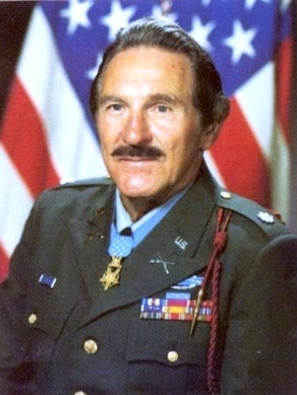 A man wearing a service uniform and medal poses for a photo.
