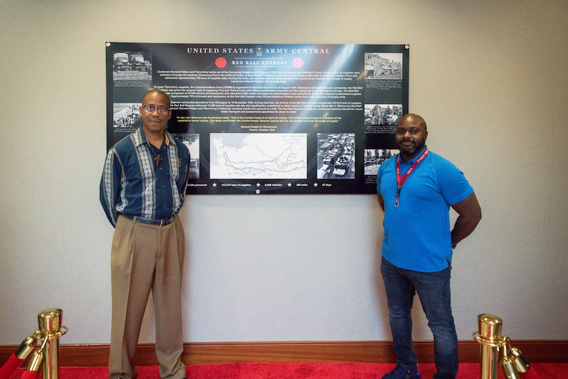 From left to right:  Mr. Samuel Allmond, USARCENT exercise planner, and Mr. Antonio Pressley, USARCENT joint exercise logistics planner, pose in front of the Red Ball Express exhibit at USARCENT's Patton Hall, Allmond and Pressley's fathers were part of the Red Ball Express logistics operation during WWII.