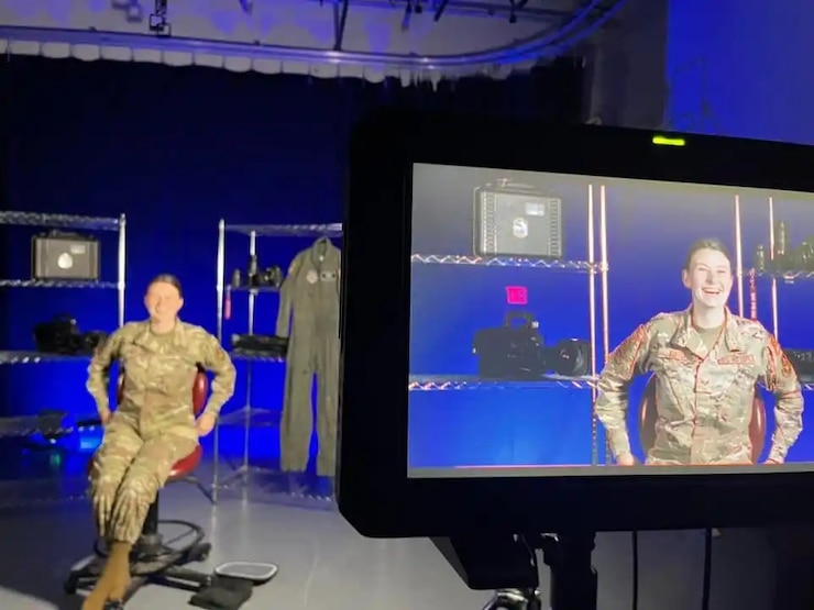 an airman looks at a laptop surrounded by computers