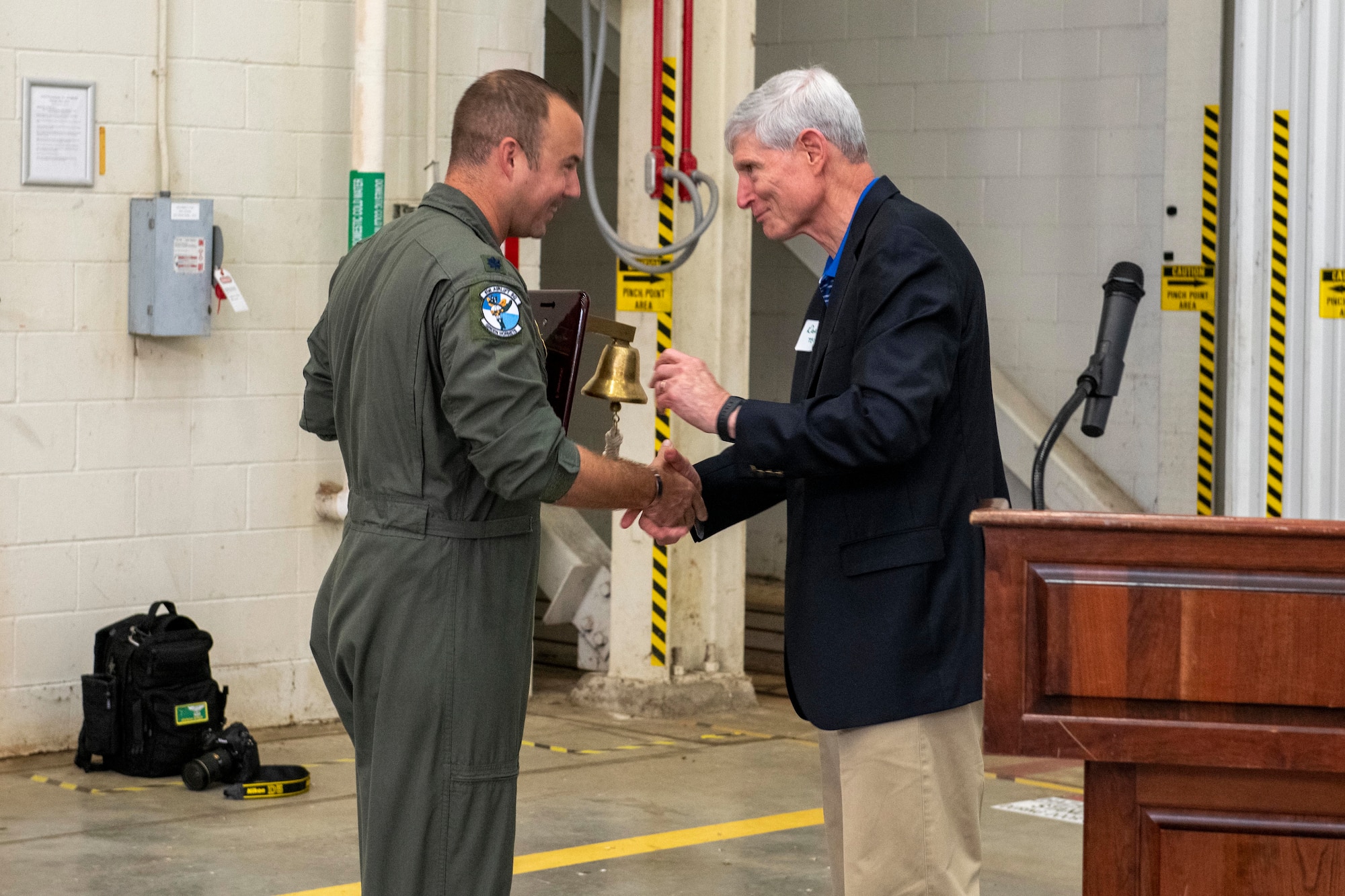 Lt. Col. Nicholas Redenius, 61st Airlift Squadron commander, is presented a bell from former Air Force Chief of Staff Gen. (ret.) Norton Schwartz, a former member of the 61st Tactical Airlift Squadron from 1977 to 1979, during a reunion visit