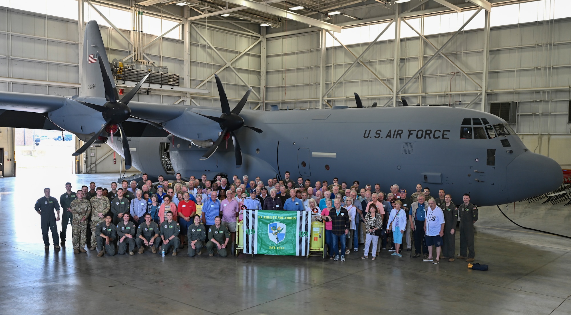 Former members of the 61st Tactical Airlift Squadron and Airmen assigned to the 61st Airlift Squadron pose for a group picture during a reunion visit