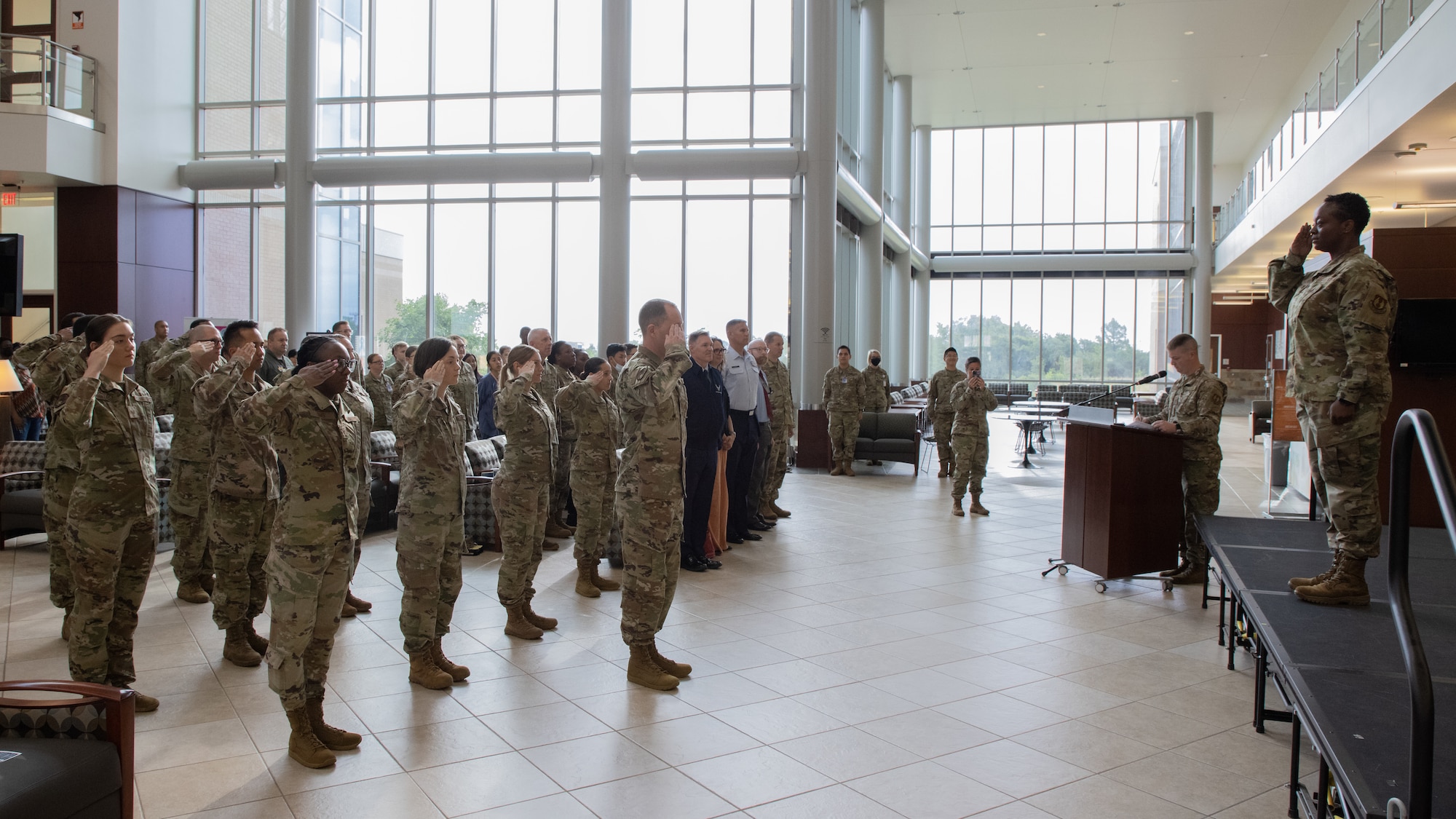 Airmen in formation saluting commander on stage