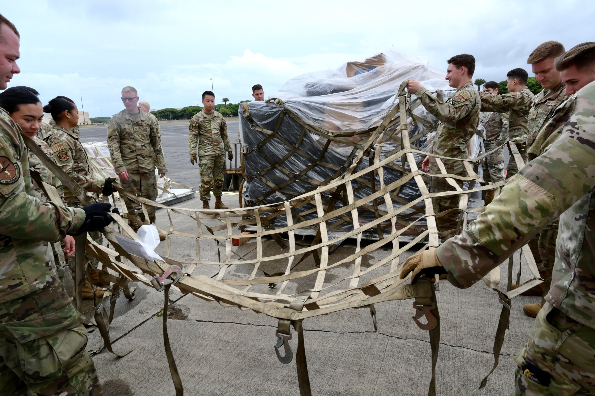 Airmen prepare to attach a cargo net to a simulated-cargo pallet during the 15th Wing’s Multi-Capable Airmen Tier 1 training event at Joint Base Pearl Harbor-Hickam, Hawaii, May 19, 2022. Tier 1 training provided Airmen with a baseline set of advanced expeditionary training tasks that all MCA will receive. (U.S. Air Force photo by 1st Lt. Benjamin Aronson)