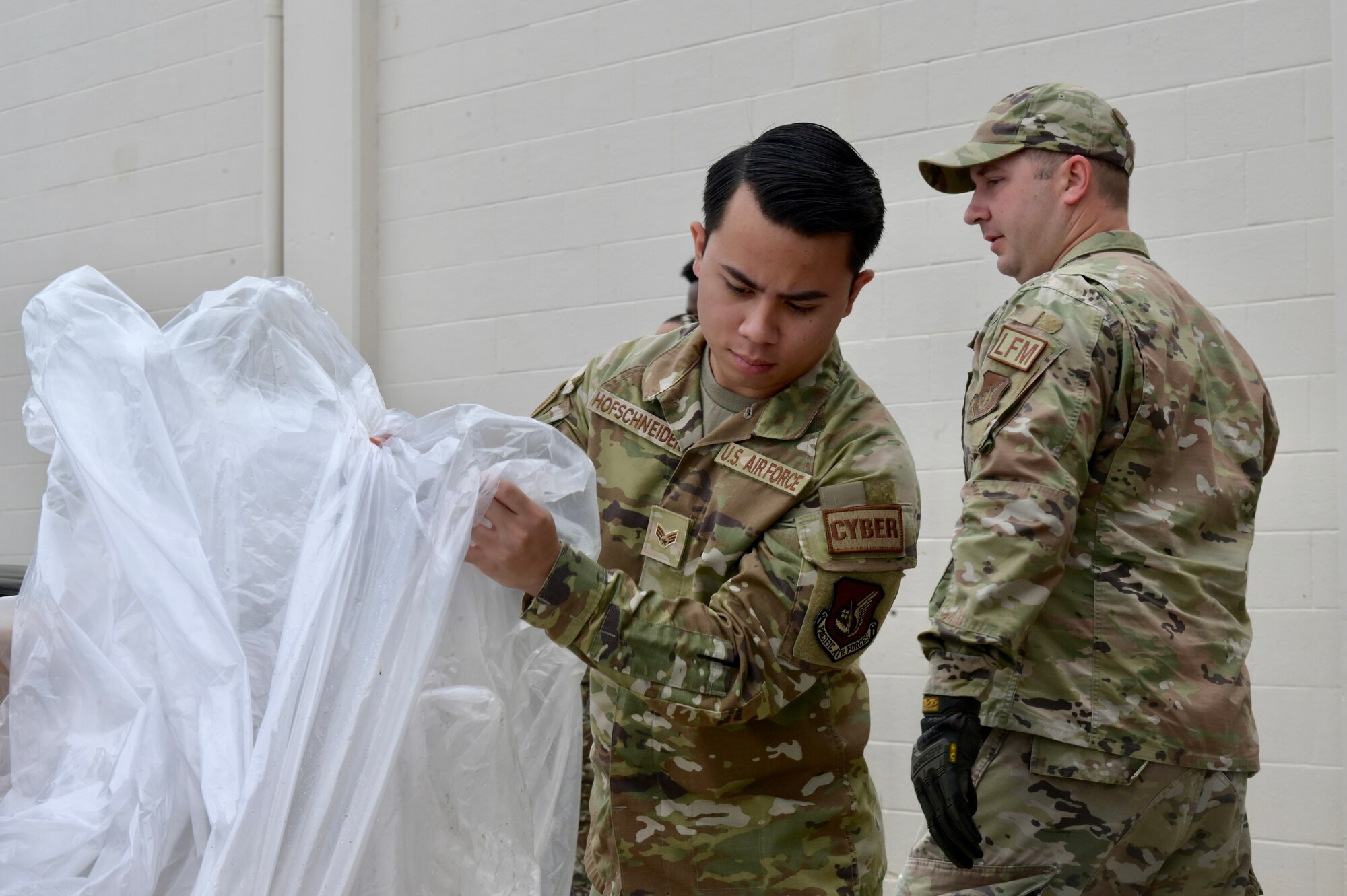 Senior Airman Edric Marco Hofschneider, 747th Cyberspace Squadron command and control defensive operator, helps to wrap a simulated-cargo pallet during the 15th Wing’s Multi-Capable Airmen Tier 1 training event at Joint Base Pearl Harbor-Hickam, Hawaii, May 19, 2022. Tier 1 training provided Airmen with a baseline set of advanced expeditionary training tasks that all MCA will receive. (U.S. Air Force photo by 1st Lt. Benjamin Aronson)