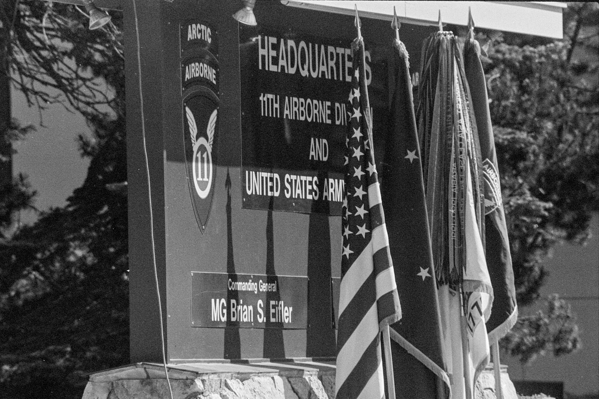 Flags stand before a sign newly bearing the 11th Airborne Division title