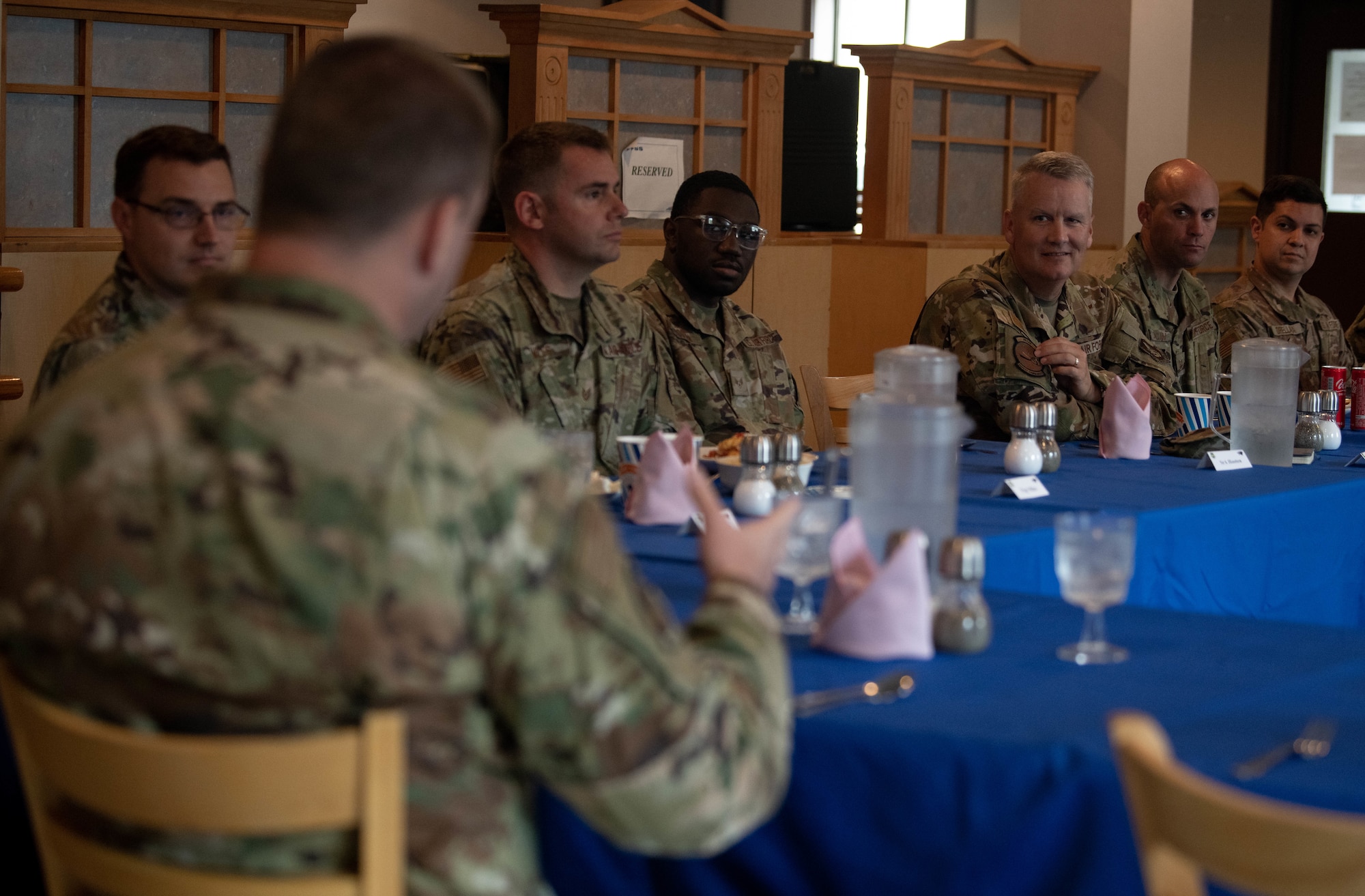 Military members have a discussion at a dining table.