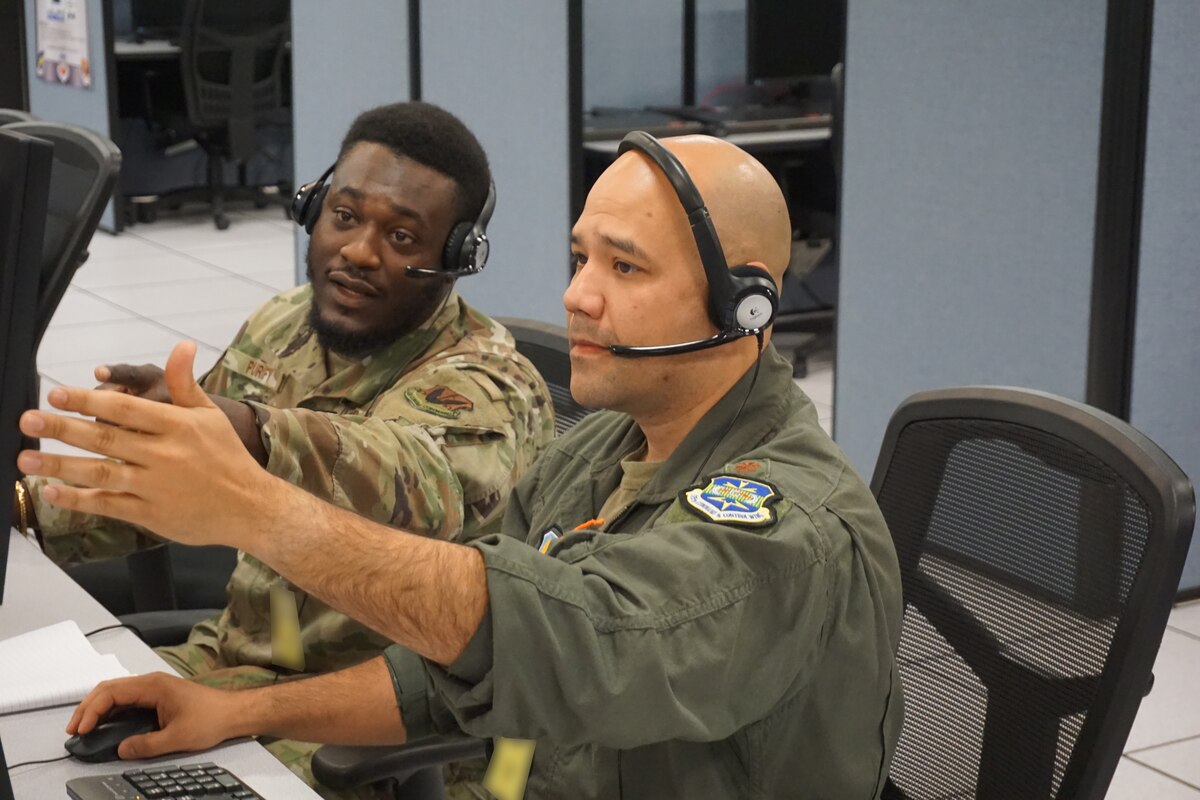photo of two USAF Airmen wearing headsets sitting at a computer