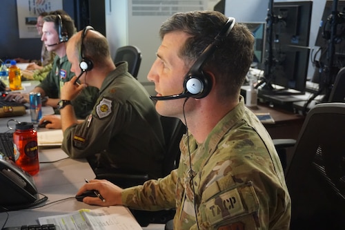 photo of four USAF Airmen wearing headsets working on computers