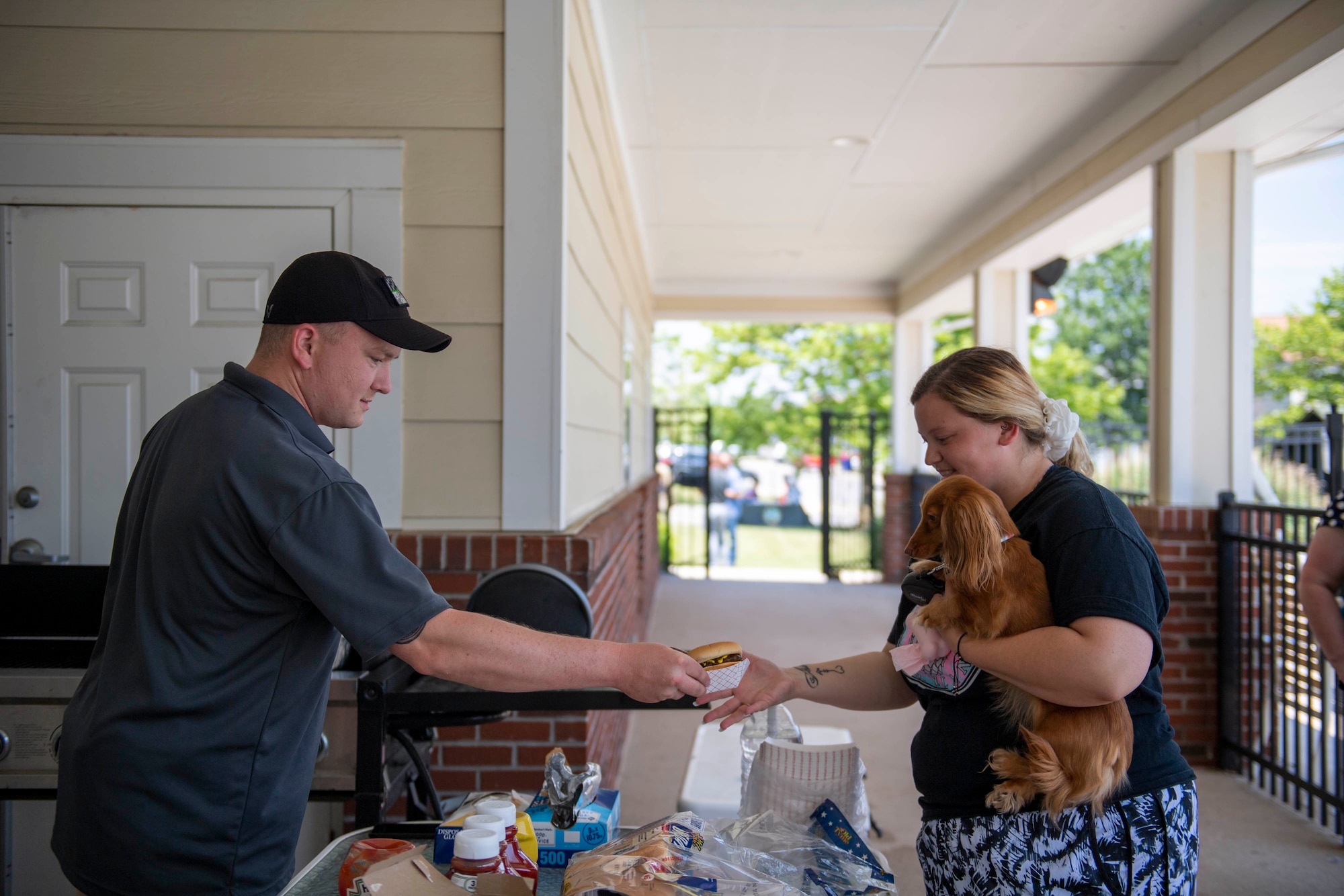 Staff Sgt. Charles Munson, 436th Civil Engineer Squadron emergency management noncommissioned officer in charge, hands a patron a hotdog, during the 2022 Hurricane Block Party at Dover Air Force Base, Delaware, June 2, 2022. The block party, sponsored by the 436th CES Emergency Management flight, offered attendees useful information pertaining to severe storms and hurricanes. Additionally, attendees toured several booths set up by local organizations and base units, offering free gifts and information. (U.S. Air Force photo by Tech. Sgt. J.D. Strong II)