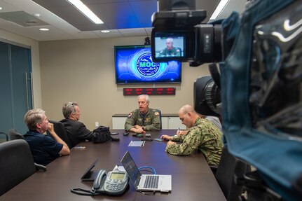 Adm. Meier speaking with news channels at a conference table