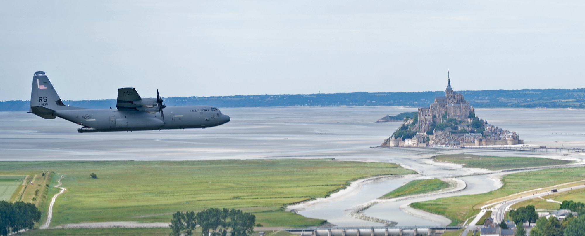 A C-130J Super Hercules aircraft assigned to the 37th Airlift Squadron out of Ramstein Air Base, Germany,  flies past Mont Saint-Michel in Normandy, France, June 2, 2022.  37th AS has a lineage that stems from squadrons that participated in the invasion of France by dropping troops and carrying gliders over Normandy in order to secure towns and bridges before the rest of the Allied Forces could storm the beaches during World War II. (U.S. Air Force photo by Capt. Matt Bilbrey)