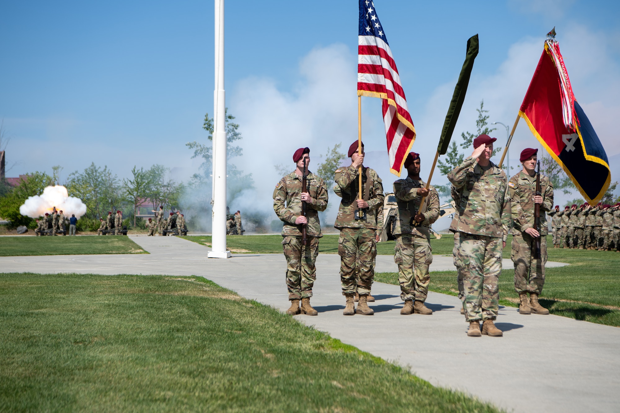 Soldiers stand in formation as howitzers fire during a ceremony