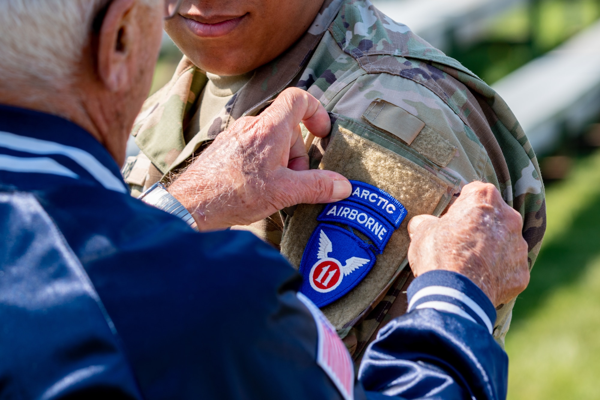 A U.S. Army veteran applies the new 11th Airborne patch to the shoulder of a Soldier