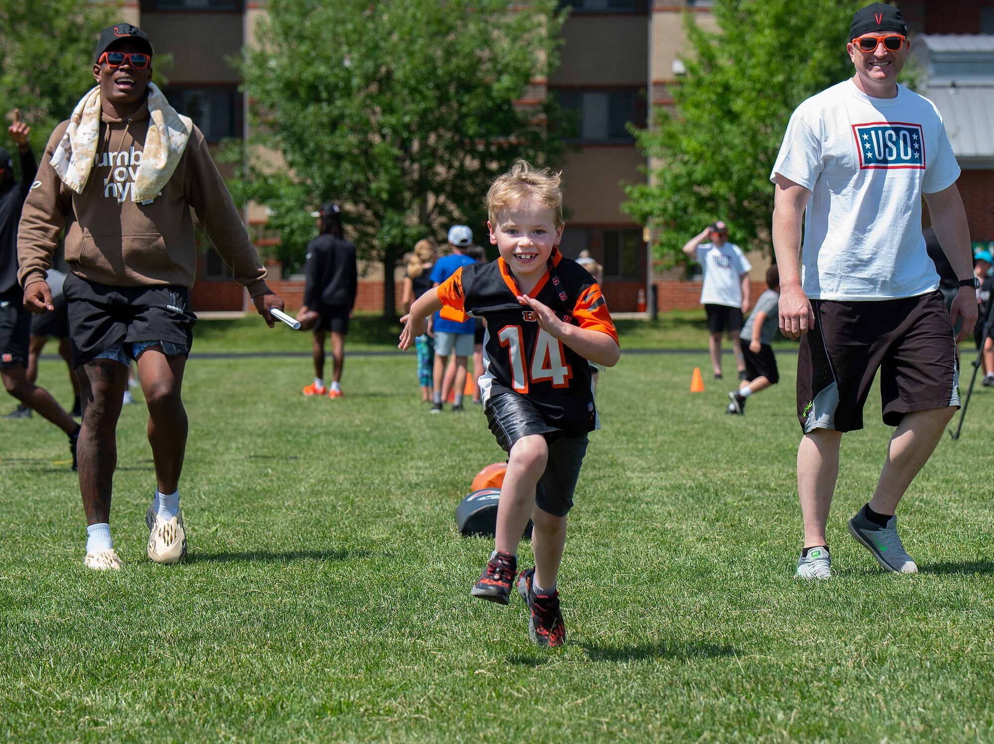 Carter Rykken, 7, sprints for the obstacle
course finish line under the eye of Cincinnati
Bengal rookie Cam Taylor-Britt (left), and a
USO volunteer during the USO-sponsored
Bengals’ skill clinic June 3, 2022, at
Wright-Patterson Air Force Base, Ohio.
Rykken was one of the 99 Wright-Patt youths
who got the chance to learn from the football
pros. (U.S. Air Force photo by R.J. Oriez)