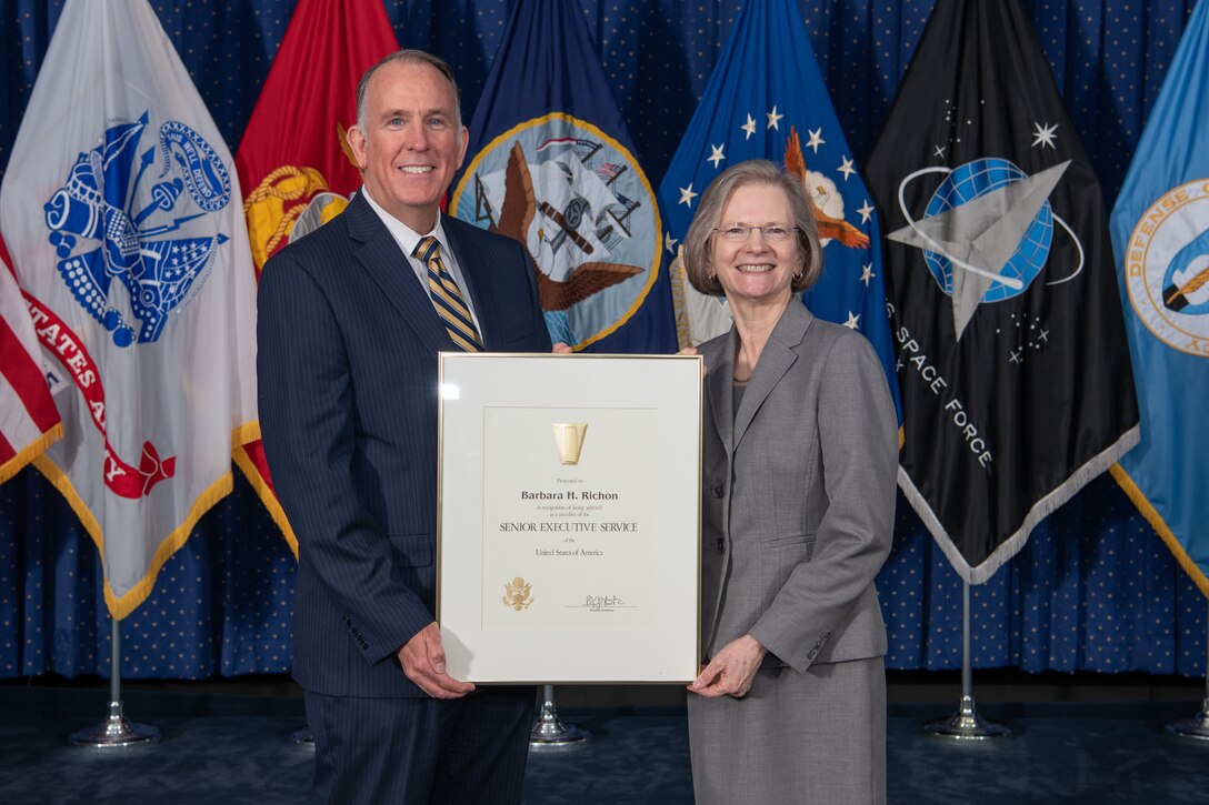 man and women in business suits holding framed senior executive service certificate