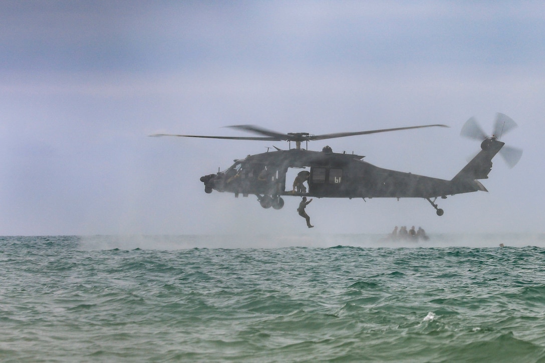 Ecuadorian troops jump from a U.S. helicopter into a body water.