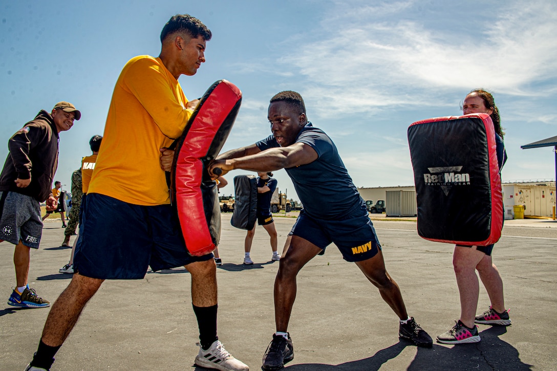 A sailor hits a baton on a punching bag during training.