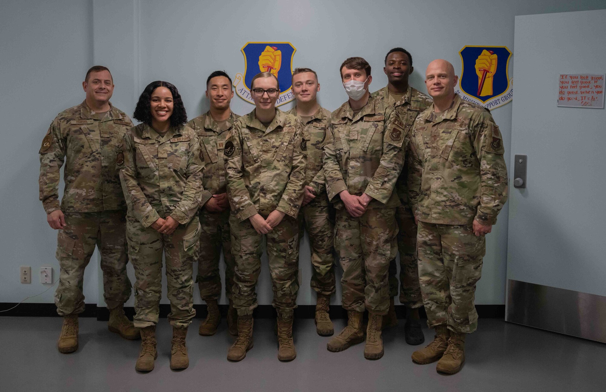 Military members stand side by side to take a group photo.