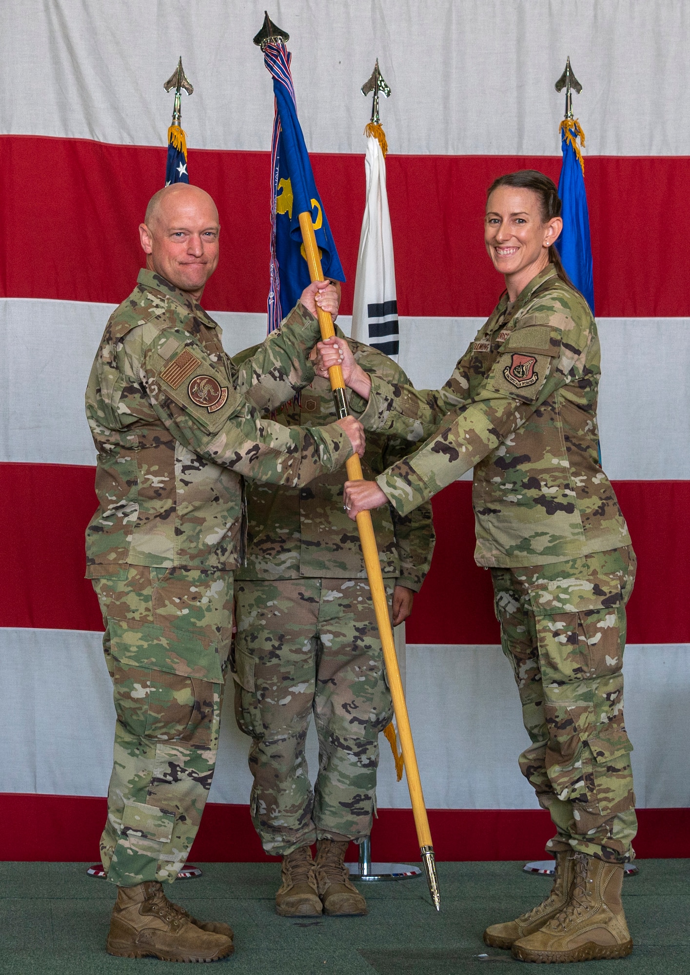 Col. Mathew Gaetke, 51st Operations Group commander, left, passes the squadron guidon to Lt. Col. Chandra Fleming, 51st Operations Support Squadron newly-appointed commander, representing her taking command of the OSS at Osan Air Base, Republic of Korea, June 7, 2022.