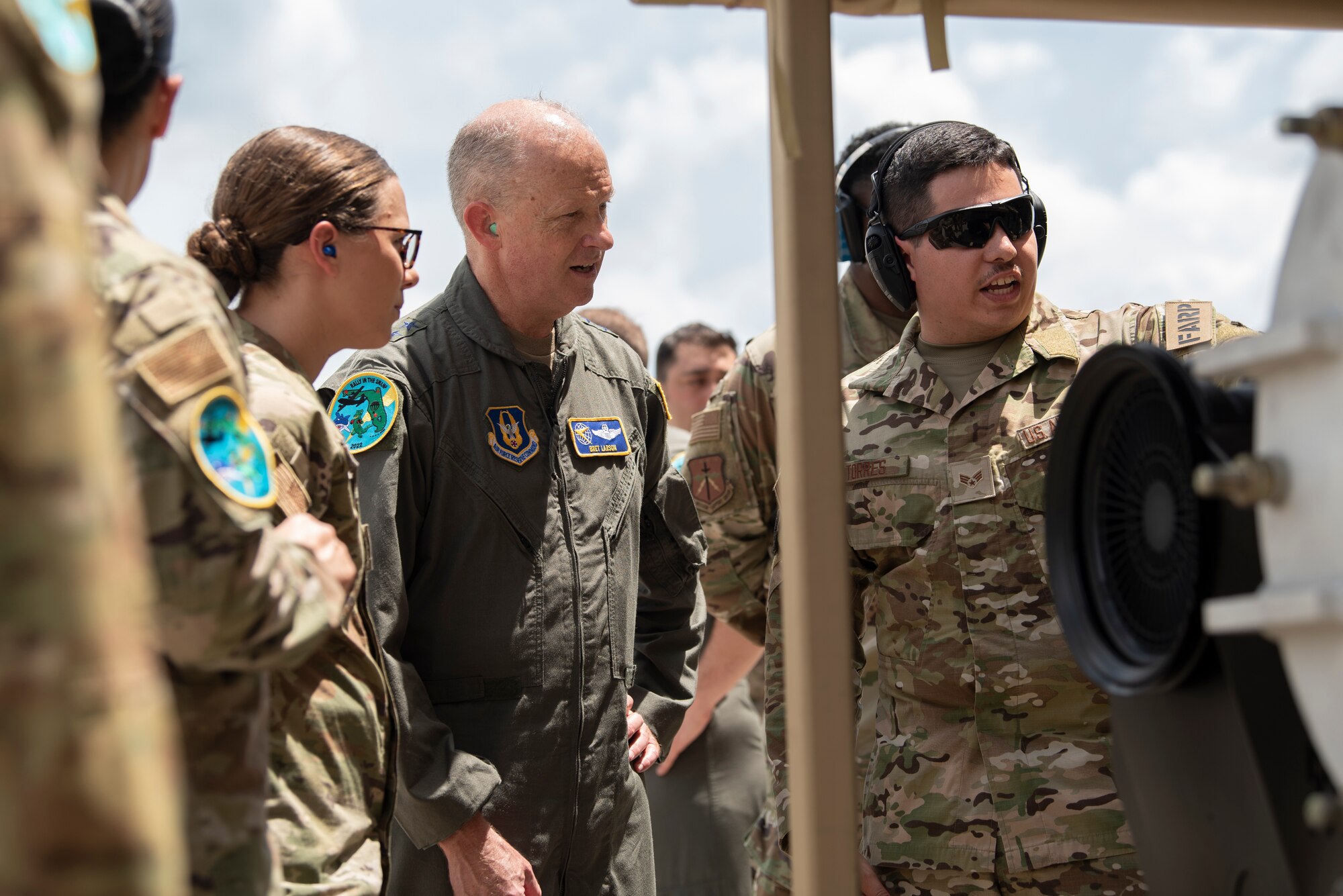 A photo of three Airmen standing in front of a STARCART.