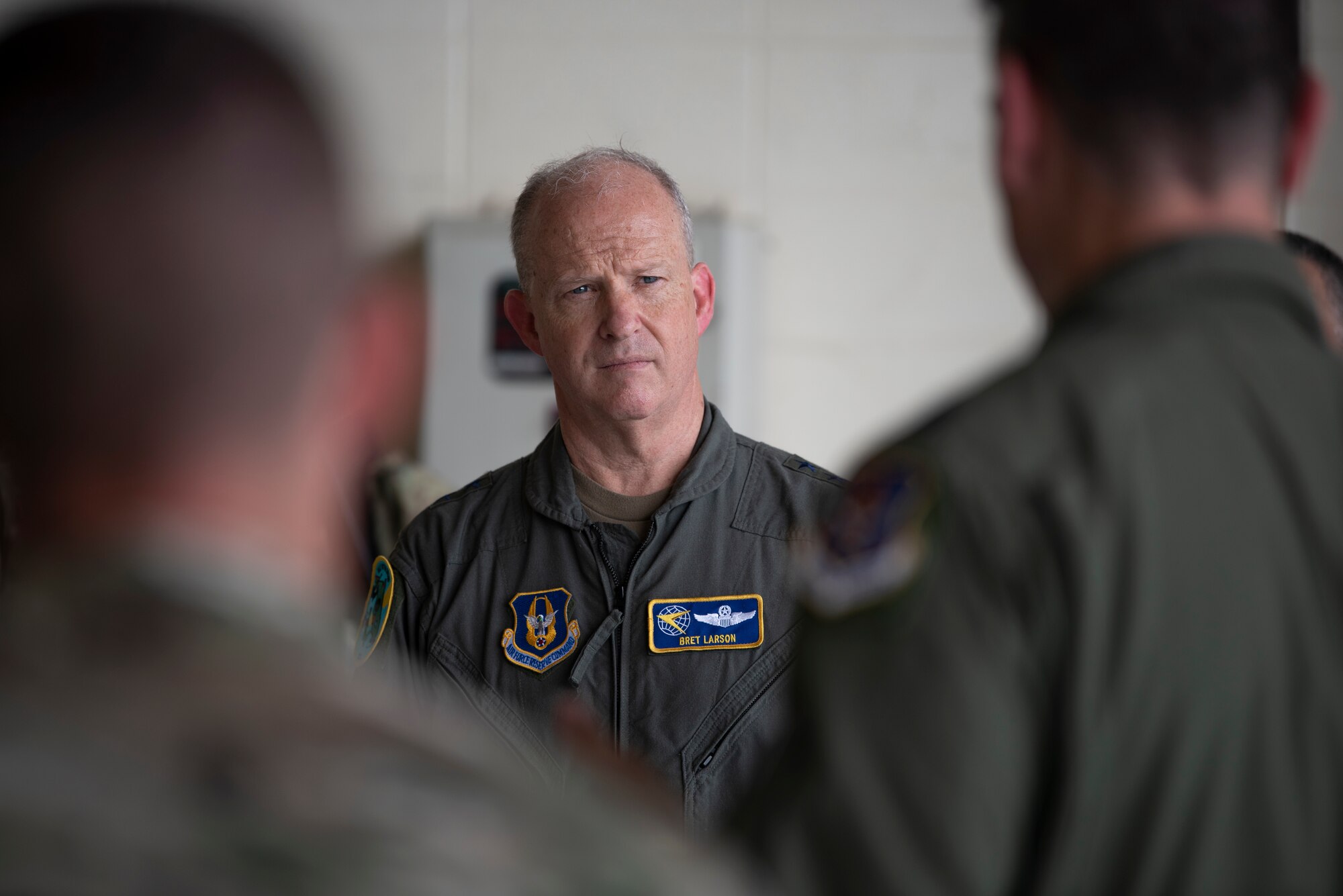 A photo of Maj. Gen. Bret C. Larson with two Airmen in the forefront blurred out.