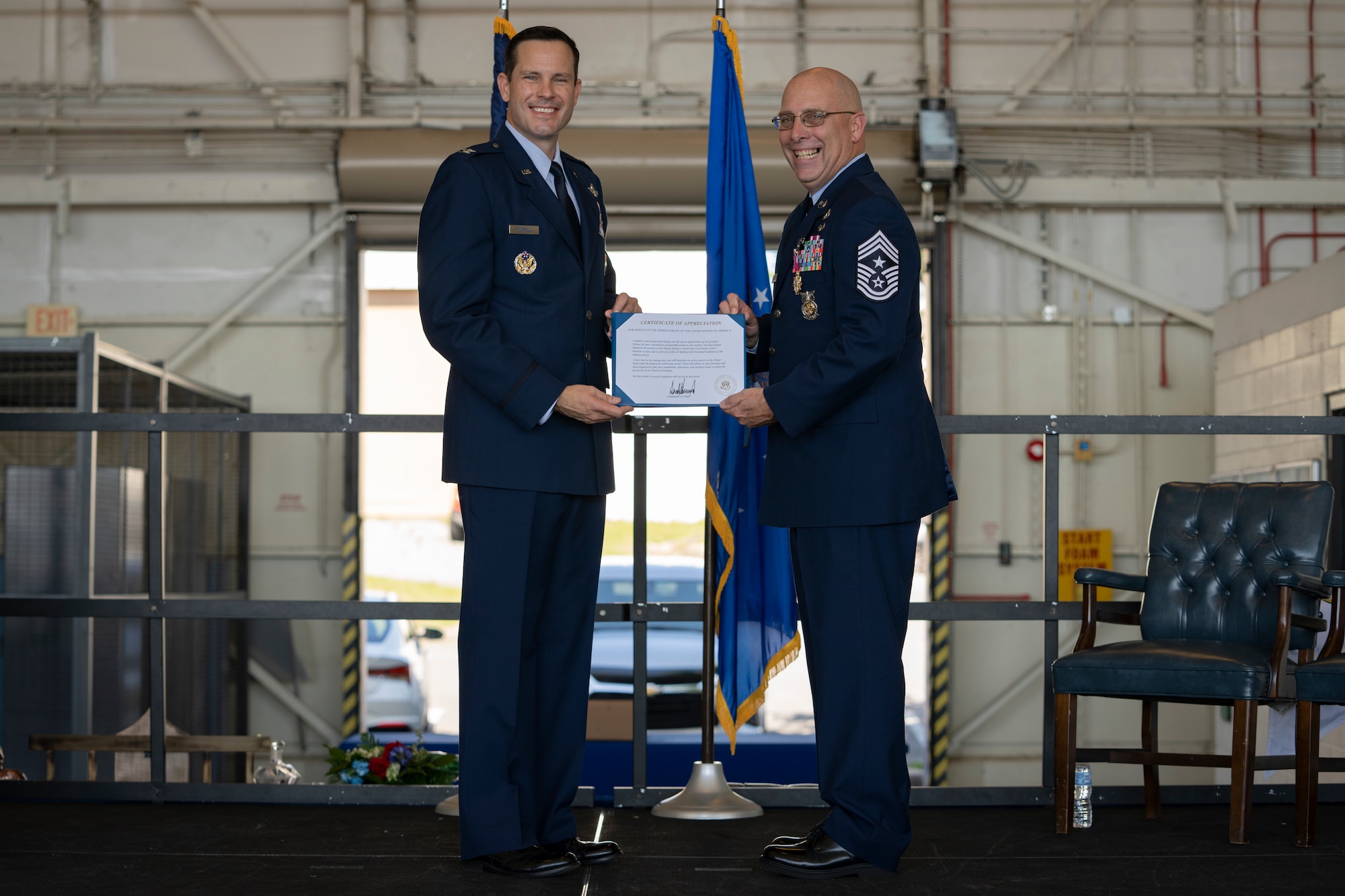 Chief Master Sgt. Peter Webb and Col. Kevin Merrill hold a retirement certificate for a photo during Webb's retirement ceremony.