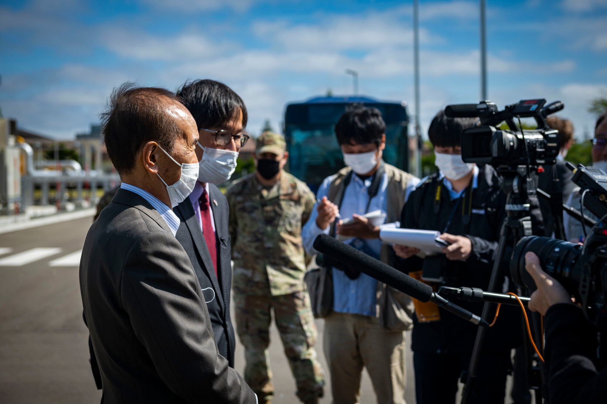 Group of interviewers stand around men in suits.