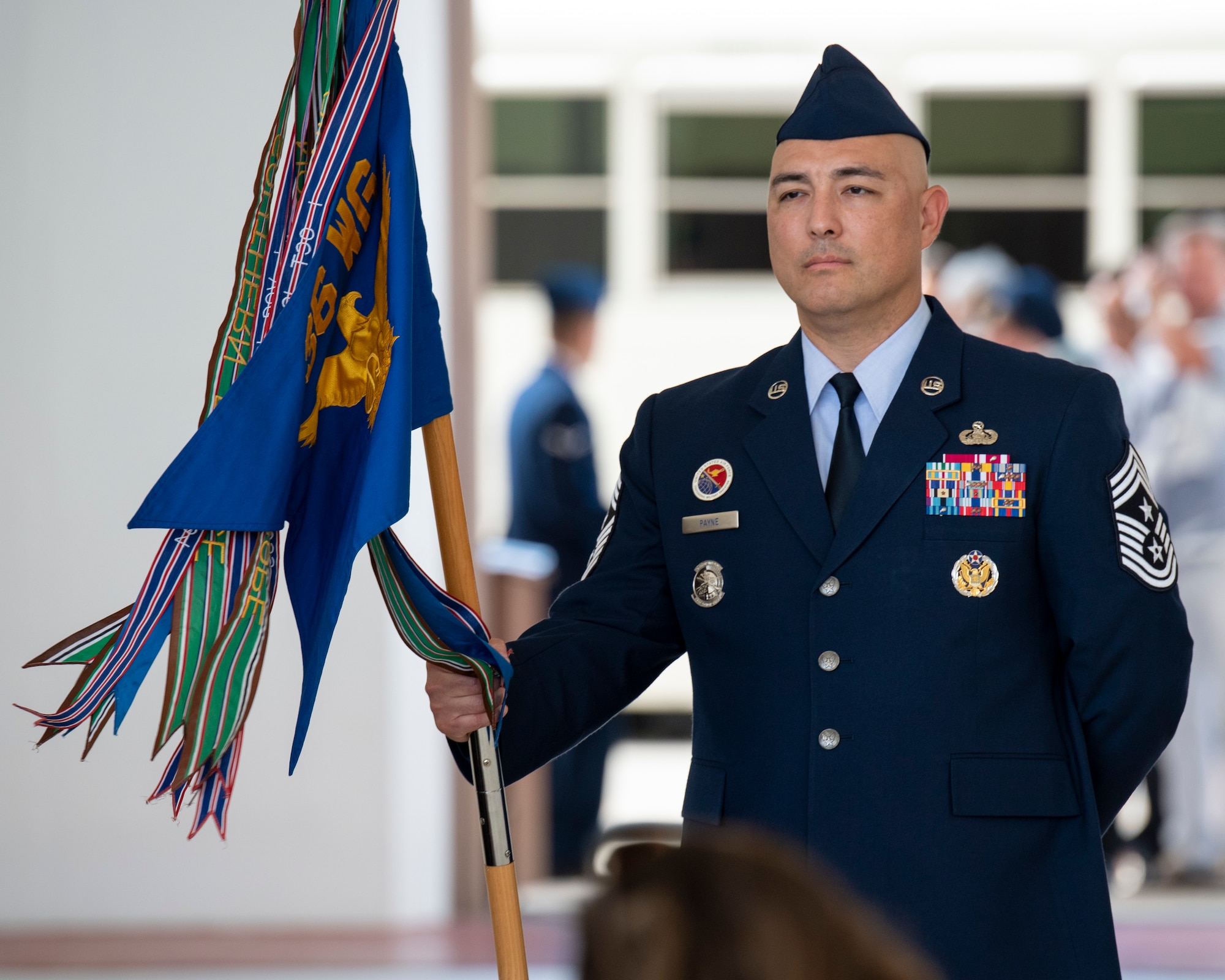 U.S. Air Force Chief Master Sgt. John E. Payne, command chief of the 36th Wing, stands ready with the guidon moments before the begining of the change of command ceremony, June 10, 2022, at Andersen Air Force Base, Guam. The 36th Wing is comprised of five groups and 18 squadrons, executing Indo-Pacific Command's Bomber Task Force, Theater Security Packages, Contingency Response Operations and peacetime and combat operations in the Indo-Pacific Region. The Wing is also tasked to ensure the successful deployment, employment and integration of air and space forces from the most forward sovereign U.S. Air Force Base in the Indo-Pacific Region. (U.S. Air Force photos by Staff Sgt. Ryan Brooks)