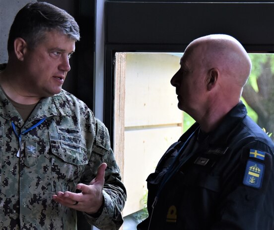 Capt. Douglas S. MacKenzie (left), Naval Supply Systems Command Fleet Logistics Center Sigonella’s commanding officer, speaks to an officer from the Swedish navy June 3, 2022, in Stockholm, prior to the beginning of exercise Baltic Operations (BALTOPS) 22, the premier maritime-focused exercise in the Baltic Region.