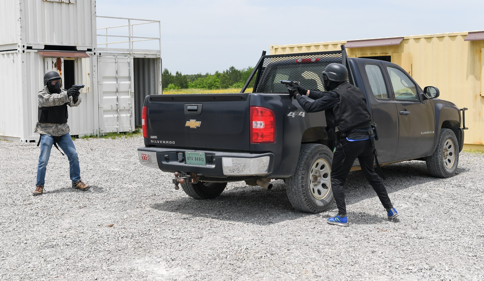 Two men in protective gear for training with Simunitions in a stand off around a truck during a mock traffic stop