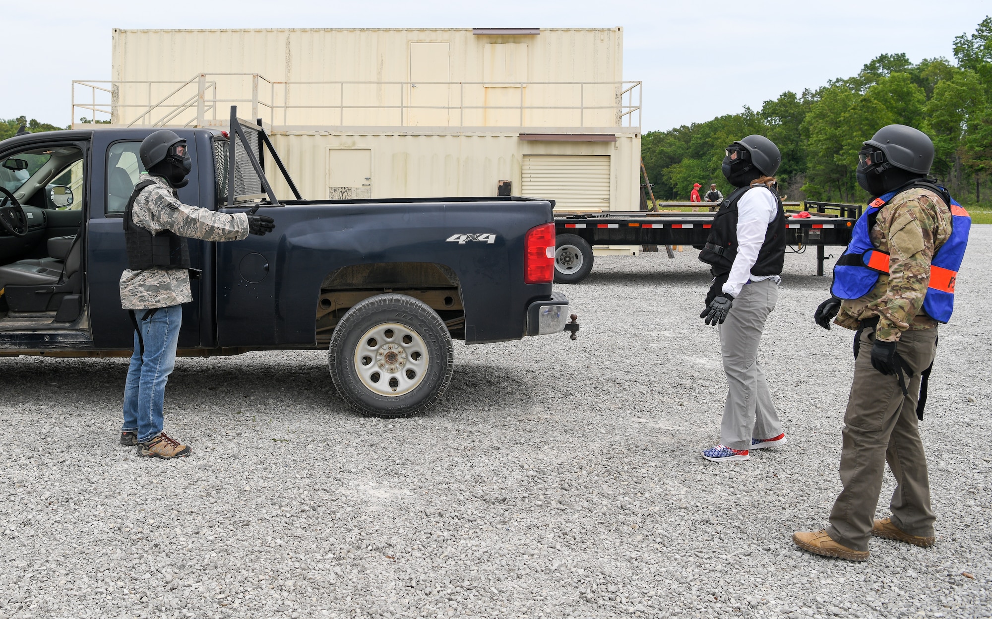 Two men and a woman in protective gear for training with Simunitions weapons engage in a mock traffic stop