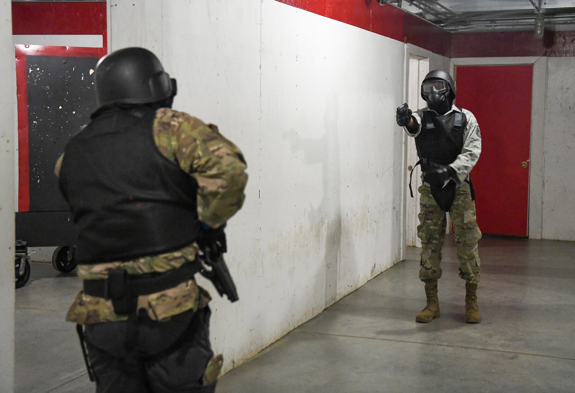 Two men with Simunitions weapons in hallway, one trying to draw weapon from holster as other fires at him