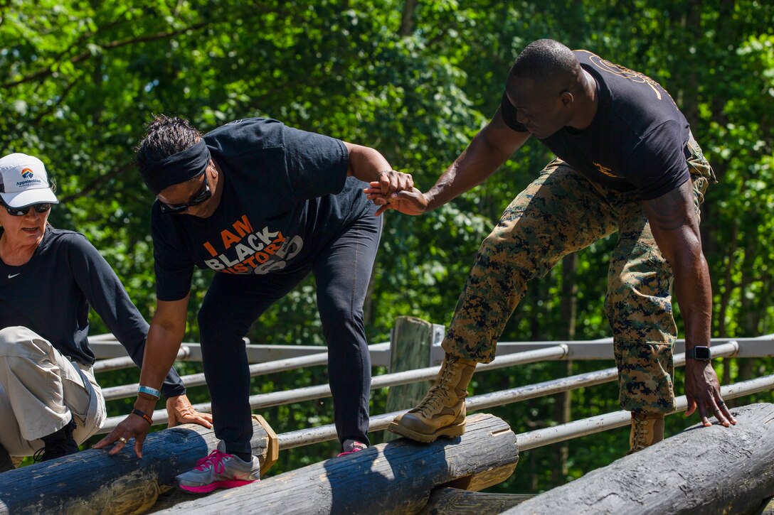 U.S. Marine Corps Staff Sgt. Alon Heywood, a Force Fitness Instructor Trainer with Martial Arts and Fitness Center of Excellence, guides Urina Holt, Veterans Upward Bound Director from Southern University of Shreveport, La., through an obstacle course during the Marine Corps Recruiting Command’s Educators' Workshop at Marine Corps Base Quantico, Va., June 9.