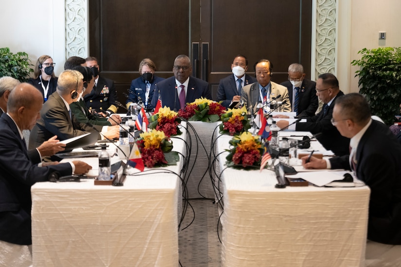 Multiple men wearing business suits participate in a meeting.