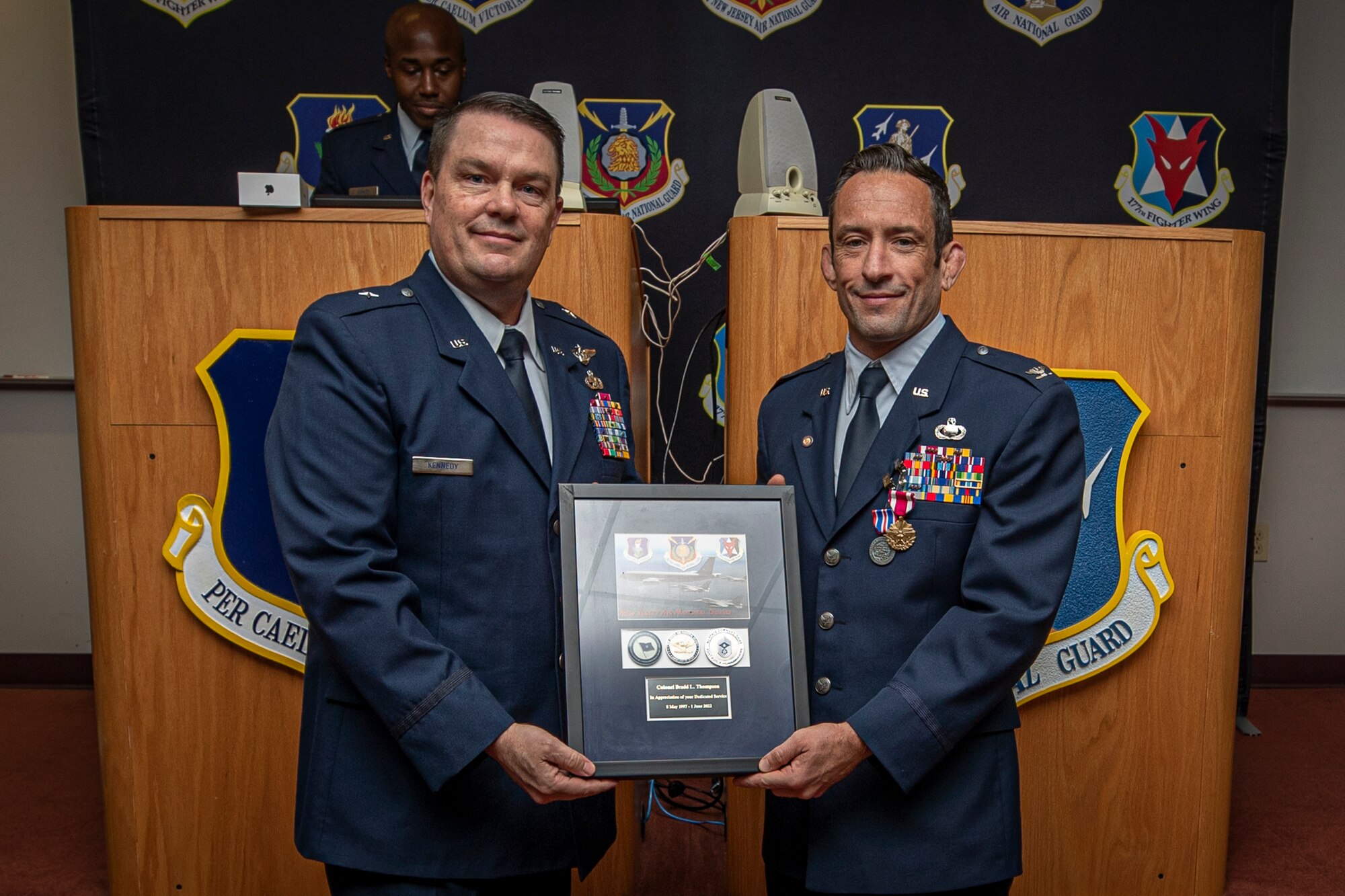 U.S. Air Force Brig. Gen. Patrick Kennedy, left, command of the New Jersey Air National Guard, presents Col. Brand Thompson with a New Jersey Joint Force Headquarters-Air memento during Thompson's retirement ceremony on Joint Base McGuire-Dix-Lakehurst, New Jersey, June 9, 2022.