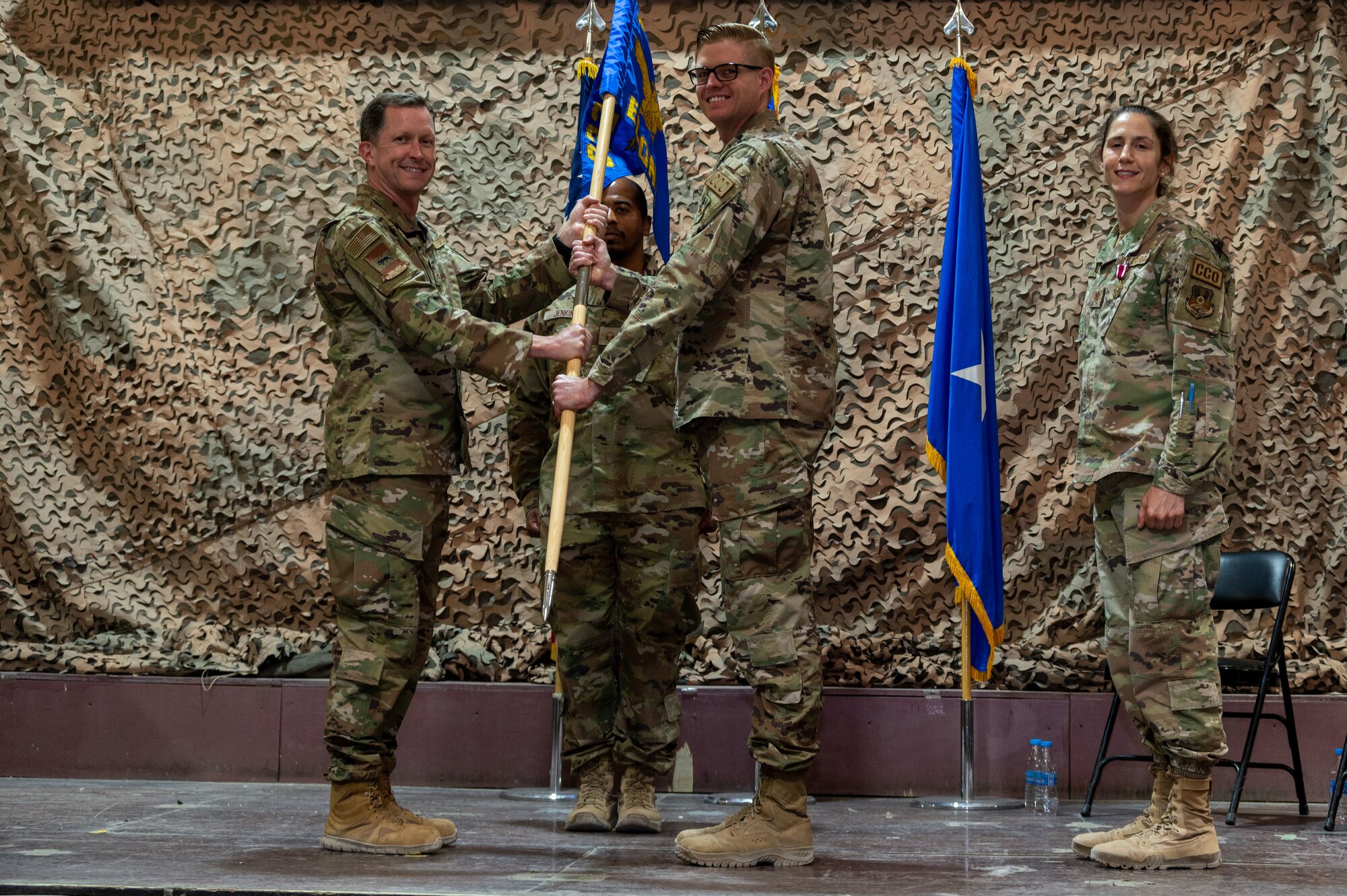 U.S. Air Force Brig. Gen. Christopher Sage, 332d Air Expeditionary Wing commander, exchanges the 332d Expeditionary Contracting Squadron guidon with U.S. Air Force Major Daniel P. Monroe, 332d ECONS incoming commander, during a change of command ceremony at an undisclosed location in Southwest Asia, June 4, 2022. A change of command ceremony is a tradition that represents a formal transfer of authority and responsibility from the outgoing commander to the incoming commander. (U.S. Air Force photo by Tech. Sgt. Lauren M. Snyder)