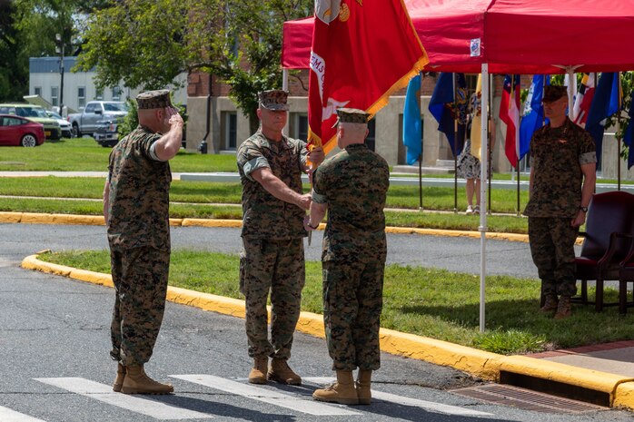 U.S. Marine Corps Brig. Gen. Arthur J. Pasagian passes the Marine Corps flag to Brig. Gen. David C. Walsh signifying the change of command at Marine Corps Systems Command during a June 9 ceremony, which at Marine Corps Base Quantico, Virginia. MCSC Sergeant Major Allen B. Goodyear salutes the two generals (U.S. Marine Corps photo by Tyler Mann).