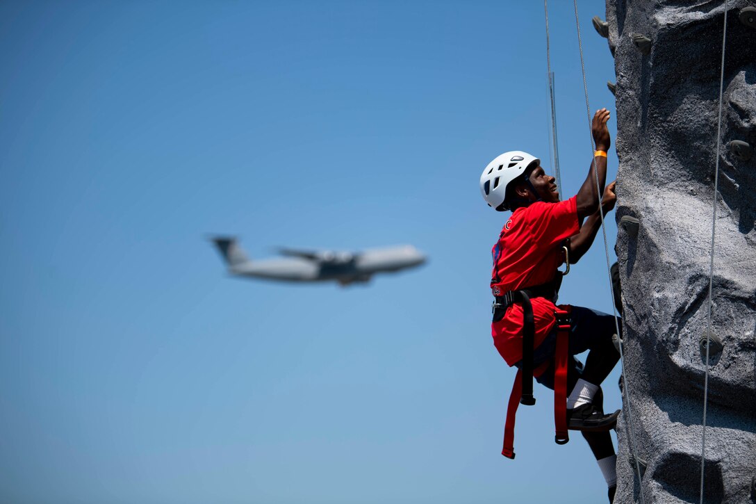 A spectator climbs a rock wall