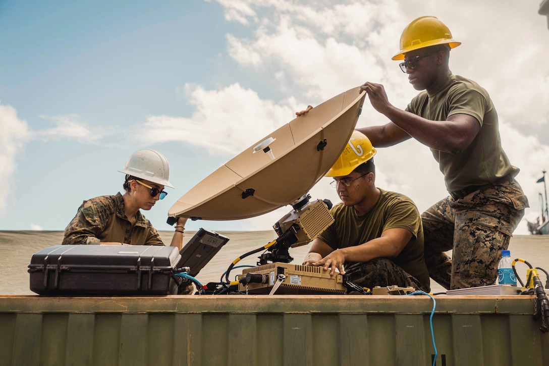 Three Marines set up a satellite.