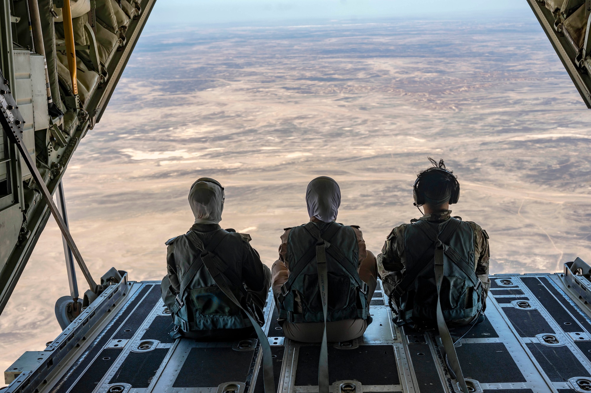 Two Royal Jordanian Air Force female pilots and a U.S. Air Force loadmaster look out from the back of a HC-130J Combat King I