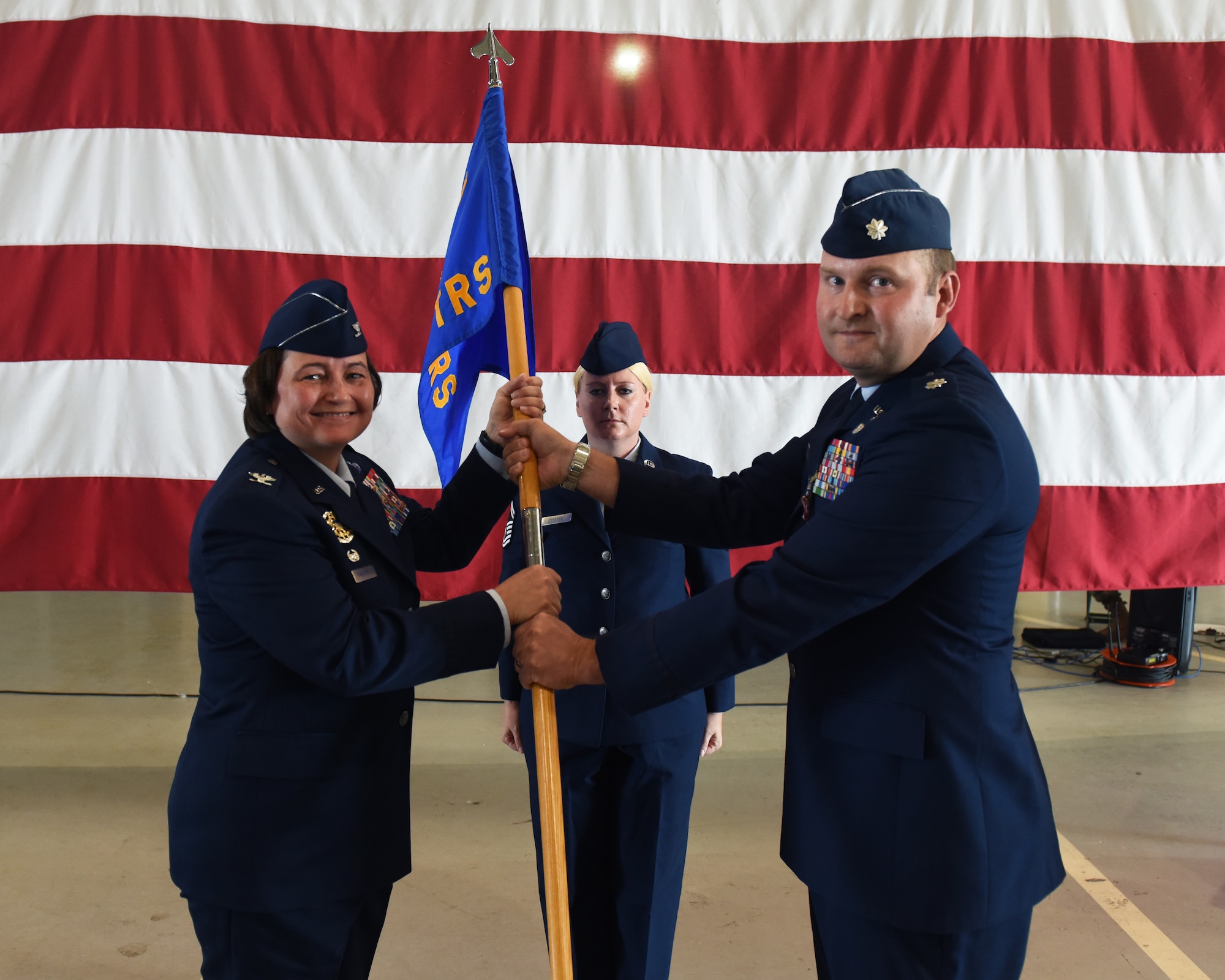 U.S. Air Force Lt. Col. John Bergmans, right, 315th Training Squadron outgoing commander, relinquishes command to Col. Angelina Maguinness, 17th Training Group commander, during the 315th TRS change of command ceremony at Goodfellow Air Force Base, Texas, June 10, 2022. Passing the guidon physically represents the symbolism of passing the squadron responsibilities to the next commander. (U.S. Air Force photo by Airman 1st Class Zachary Heimbuch)