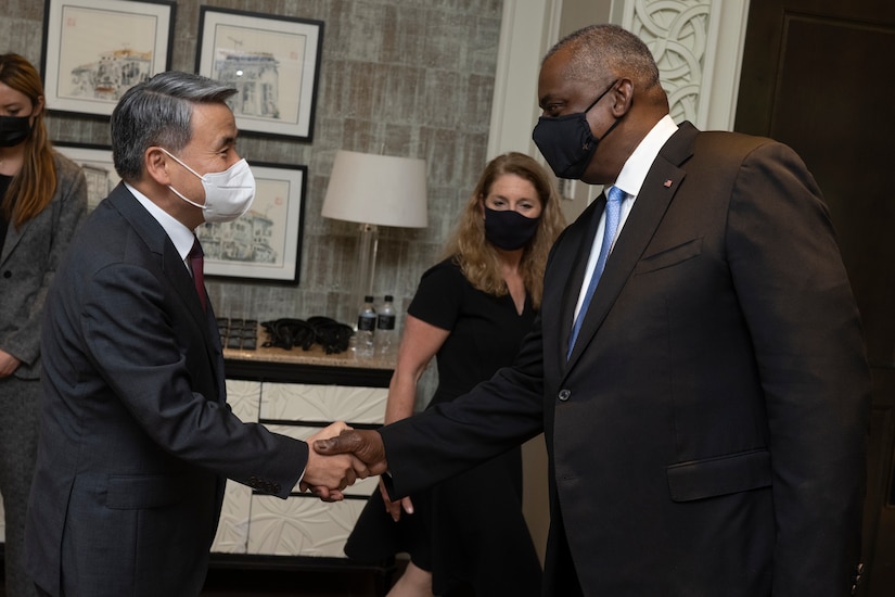 Two men wearing masks shake hands.