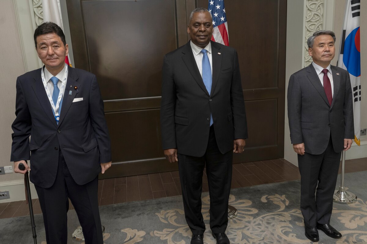 Three men stand and pose for a photo.