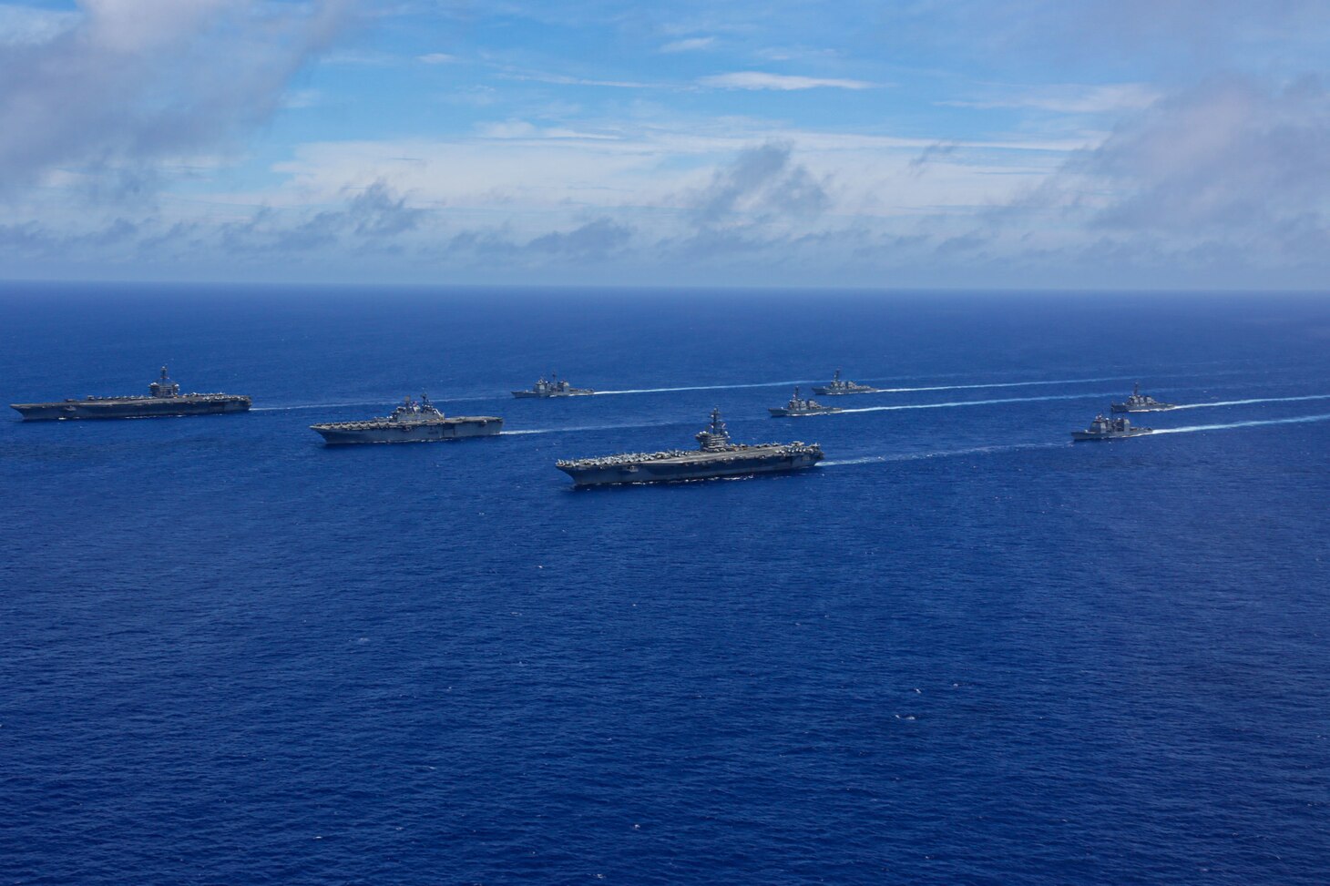 PHILIPPINE SEA (June 12, 2022) The Nimitz-class aircraft carrier USS Abraham Lincoln (CVN 72), front left, America-class amphibious assault ship USS Tripoli (LHA 7), front center, Nimitz-class aircraft carrier USS Ronald Reagan (CVN 76), front right, Ticonderoga-class guided-missile cruiser USS Mobile Bay (CG 53), middle left, Arleigh Burke-class guided-missile destroyer USS Benfold (DDG 65), middle center, Ticonderoga-class guided-missile cruiser USS Antietam (CG 54), middle right, Arleigh Burke-class guided-missile destroyer USS Spruance (DDG 111), back left, and Arleigh Burke-class guided-missile destroyer USS Fitzgerald (DDG 62) sail in formation during Valiant Shield 2022 (VS22). VS22 is a U.S.-only, biennial field training exercise (FTX) focused on integration of joint training in a multi-domain environment. This training builds real-world proficiency in sustaining joint forces through detecting, locating, tracking, and engaging units at sea, in the air, on land, and in cyberspace in response to a range of mission areas. (U.S. Navy photo by Mass Communication Specialist Seaman Aleksandr Freutel)
