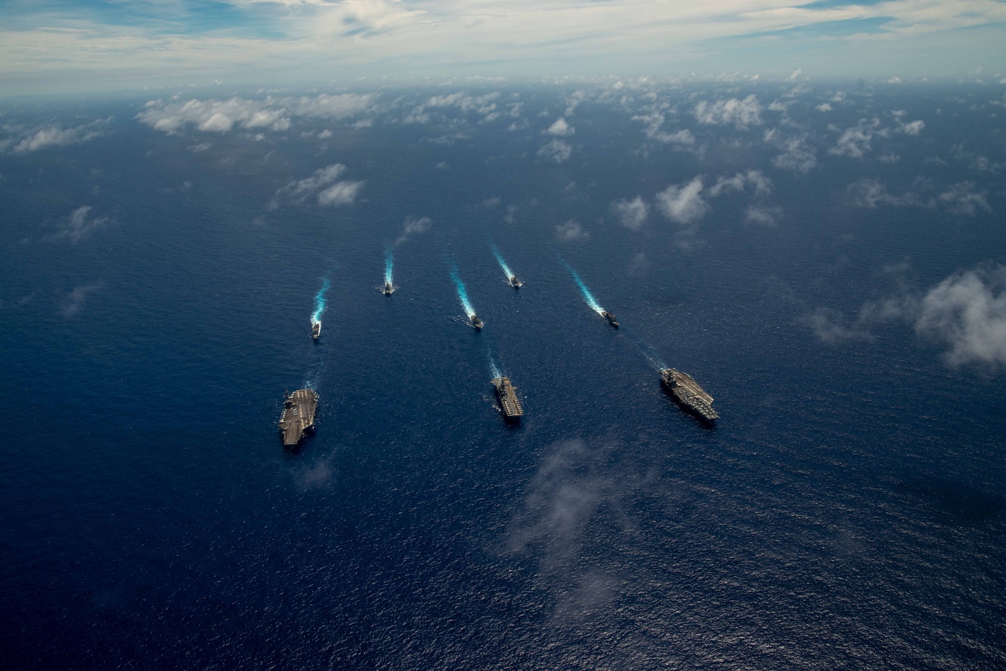 PHILIPPINE SEA (June 12, 2022) The Nimitz-class aircraft carrier USS Abraham Lincoln (CVN 72), front left, America-class amphibious assault ship USS Tripoli (LHA 7), front center, Nimitz-class aircraft carrier USS Ronald Reagan (CVN 76), front right, Ticonderoga-class guided-missile cruiser USS Mobile Bay (CG 53), middle left, Arleigh Burke-class guided-missile destroyer USS Benfold (DDG 65), middle center, Ticonderoga-class guided-missile cruiser USS Antietam (CG 54), middle right, Arleigh Burke-class guided-missile destroyer USS Spruance (DDG 111), back left, and Arleigh Burke-class guided-missile destroyer USS Fitzgerald (DDG 62) sail in formation during Valiant Shield 2022 (VS22). VS22 is a U.S.-only, biennial field training exercise (FTX) focused on integration of joint training in a multi-domain environment. This training builds real-world proficiency in sustaining joint forces through detecting, locating, tracking, and engaging units at sea, in the air, on land, and in cyberspace in response to a range of mission areas. (U.S. Navy photo by Mass Communication Specialist Seaman Aleksandr Freutel)