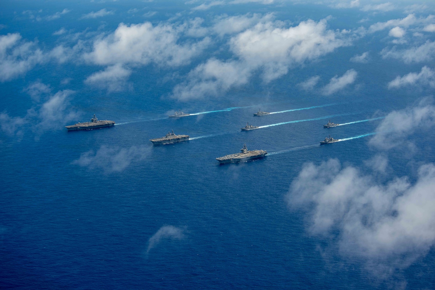 PHILIPPINE SEA (June 12, 2022) The Nimitz-class aircraft carrier USS Abraham Lincoln (CVN 72), front left, America-class amphibious assault ship USS Tripoli (LHA 7), front center, Nimitz-class aircraft carrier USS Ronald Reagan (CVN 76), front right, Ticonderoga-class guided-missile cruiser USS Mobile Bay (CG 53), middle left, Arleigh Burke-class guided-missile destroyer USS Benfold (DDG 65), middle center, Ticonderoga-class guided-missile cruiser USS Antietam (CG 54), middle right, Arleigh Burke-class guided-missile destroyer USS Spruance (DDG 111), back left, and Arleigh Burke-class guided-missile destroyer USS Fitzgerald (DDG 62) sail in formation during Valiant Shield 2022 (VS22). VS22 is a U.S.-only, biennial field training exercise (FTX) focused on integration of joint training in a multi-domain environment. This training builds real-world proficiency in sustaining joint forces through detecting, locating, tracking, and engaging units at sea, in the air, on land, and in cyberspace in response to a range of mission areas. (U.S. Navy photo by Mass Communication Specialist Seaman Aleksandr Freutel)