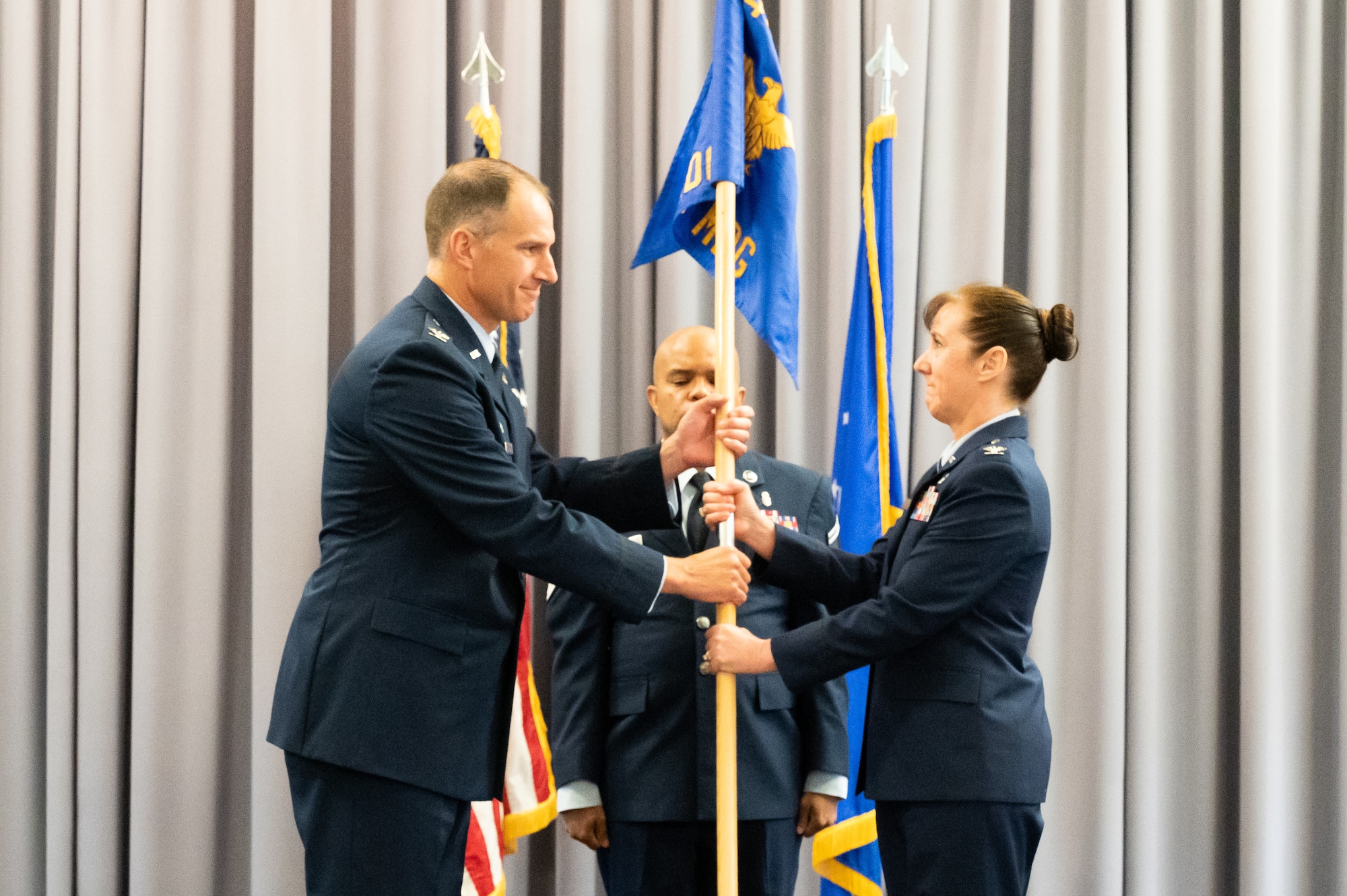 Col. Tracy Allen, right, outgoing 436th Medical Group commander, passes the guidon to Col. Matt Husemann, 436th Airlift Wing commander, during the 436th MDG Change of Command ceremony at Dover Air Force Base, Delaware, June 9, 2022. During the ceremony Allen relinquished command of the 436th MDG to Col. Peggy Dickson. (U.S. Air Force photo by Mauricio Campino)