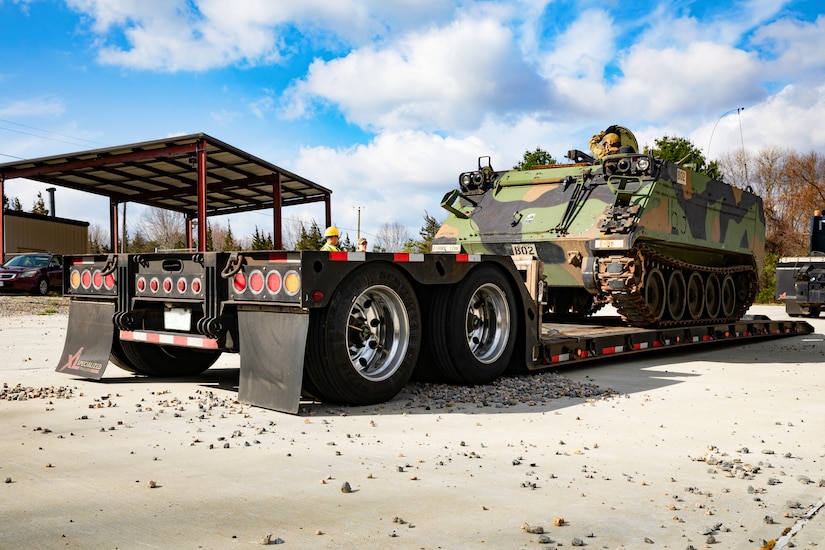 A soldier climbs into and closes the hatch on an armored military vehicle.