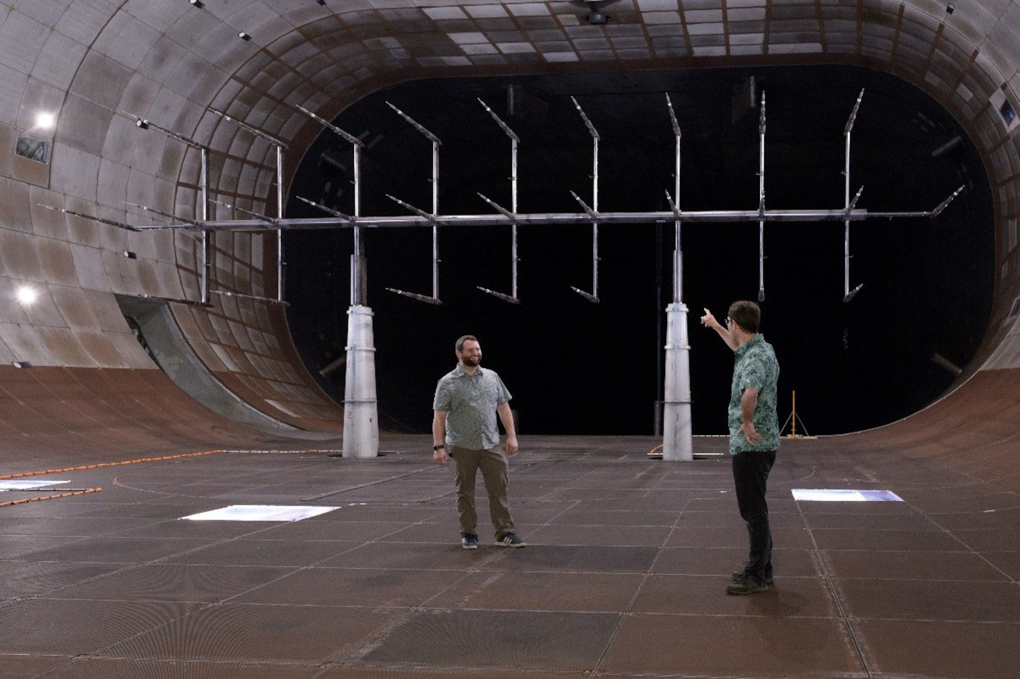 Kyle Lukacovic, a test engineer at the National Full-Scale Aerodynamics Complex (NFAC), left, and Paul Gilles, an NFAC instrumentation engineer, look around the 40-foot by 80-foot Wind Tunnel of NFAC at Moffett Field, Calif., where a flow characterization study was recently completed. During the multi-phased effort, updates were made to the existing flow calibration and characterization in the tunnel. Pictured behind Giles and Lukacovic is the test rig used for the flow evaluation. NFAC is an operating location of the 716th Test Squadron, 804th Test Group, Arnold Engineering Development Complex. (U.S. Air Force photo) (This image was altered by obscuring a badge for security purposes)