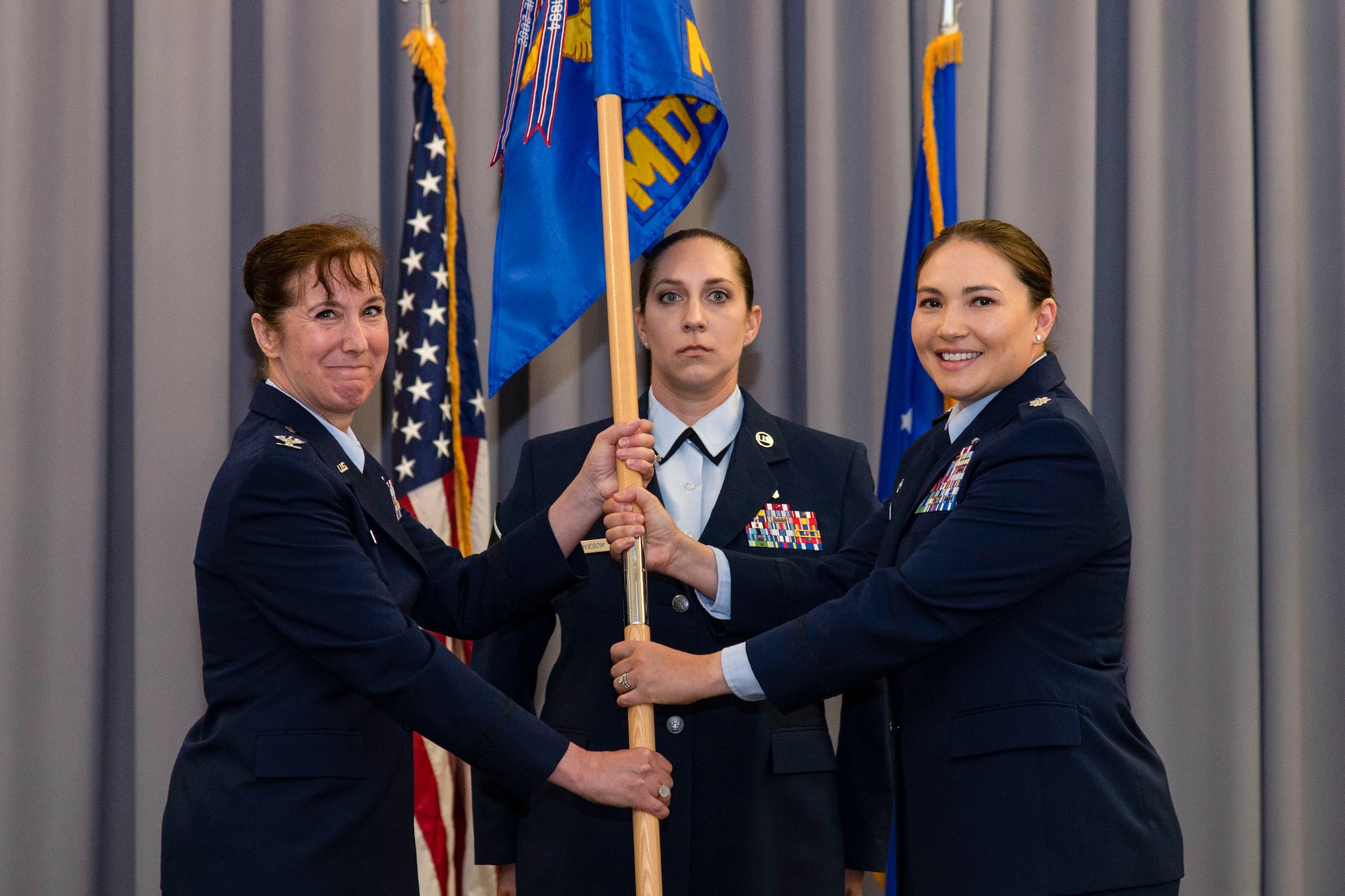 Lt. Col. Kristen Carter, right, outgoing 436th Medical Support Squadron commander, relinquishes command of the 436th MDSS after handing the guidon to Col. Tracy Allen, left, 436th Medical Group commander, at The Landings on Dover Air Force Base, Delaware, June 9, 2022. Constituted in 1992, the 436th MDSS held an inactivation ceremony and was the first of four ceremonies conducted within the 436th MDG. Guidon bearer for the ceremony was Master Sgt. Amy Schwiesow, center, 436th MDSS superintendent. (U.S. Air Force photo by Roland Balik)